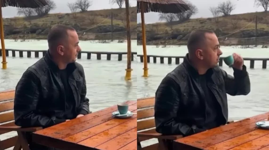Ndodh edhe kjo: Qytetari i merr me sportivitet përmbytjet, del pi kafe në shi me ujin në gjunjë